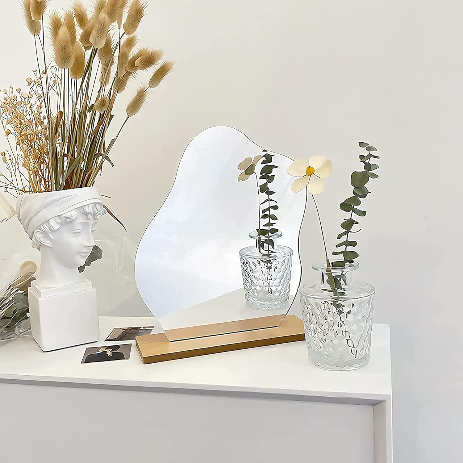 Close-up of frameless decorative mirror with organic silhouette and wooden base