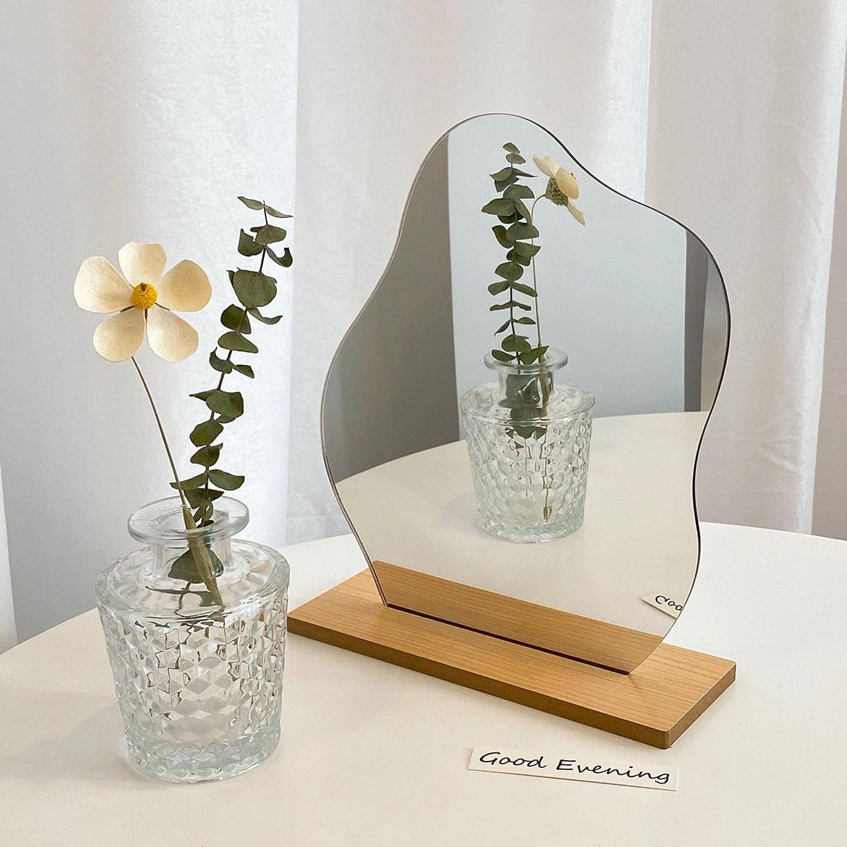 Irregular frameless decorative mirror on a wooden base displayed on a flat surface