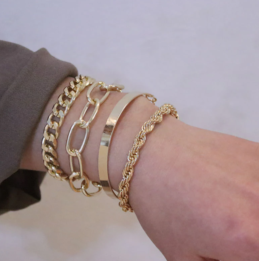 Metal bracelet set featuring multiple chain link designs worn together