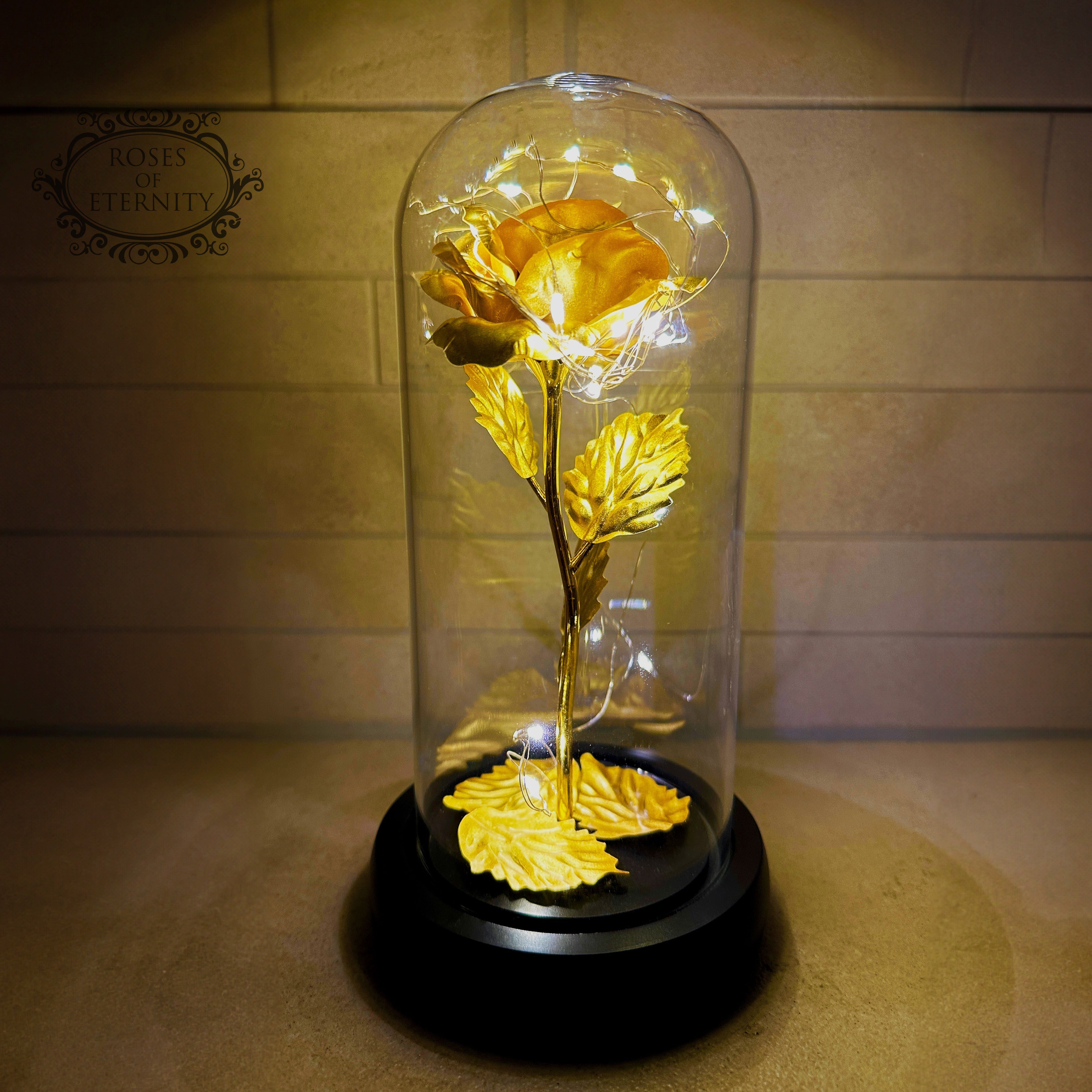 Glass dome home décor piece featuring an artificial flower with built-in LED lighting and wooden stand