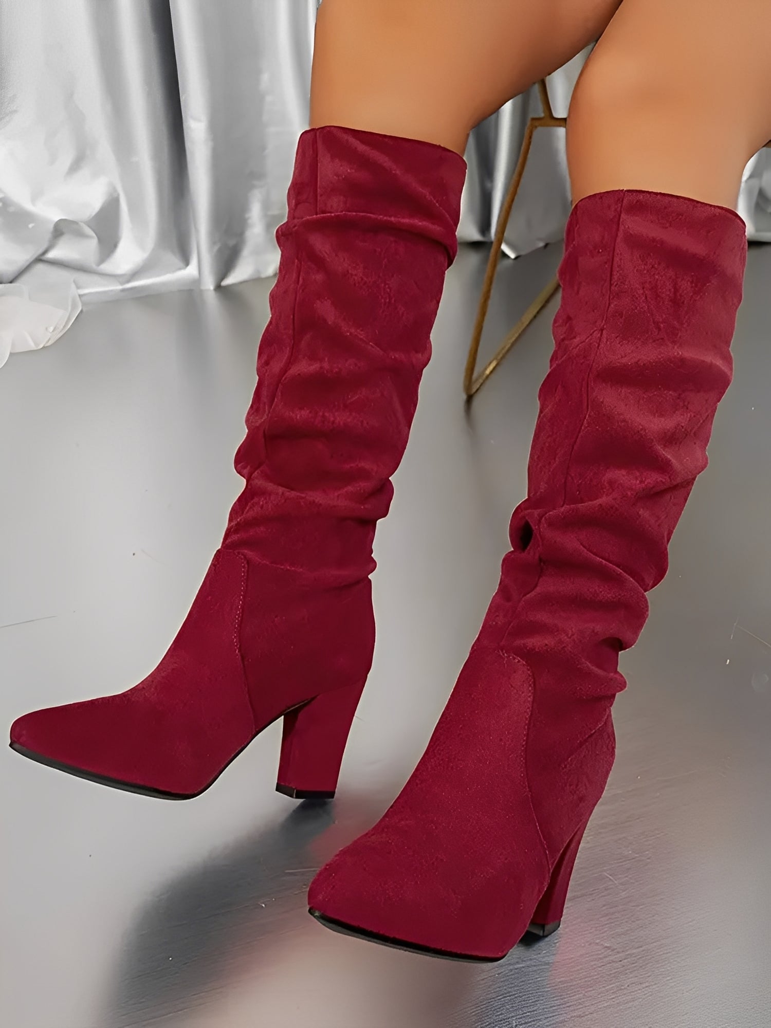 Pair of women's knee-high heeled boots displayed at an angle showing full shaft length