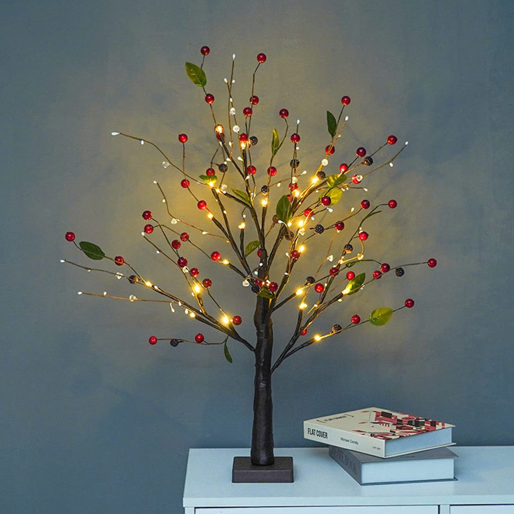 LED decorative fir tree with berries and warm glowing lights on a table