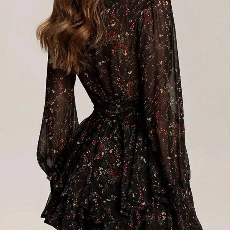 Short women's dress featuring a floral all-over pattern, high collar, and elastic cuffs on sheer sleeves