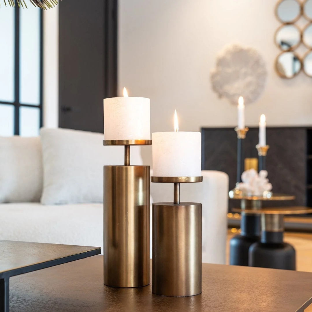 Brushed brass candlestick holders in small, medium, and large sizes arranged in a row
