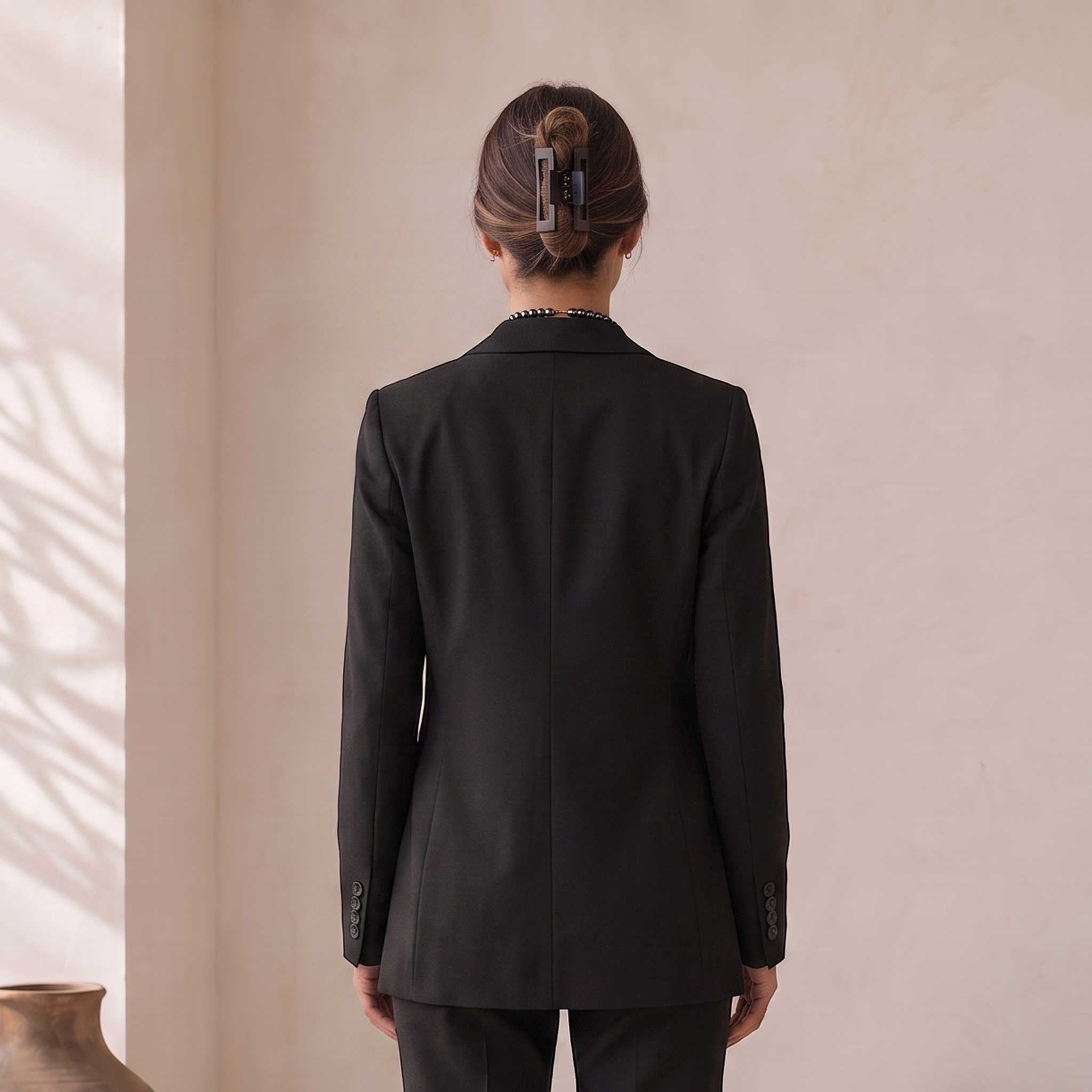 Close-up of women's suit blazer lapel and single-breasted button closure from a three-piece tailored set
