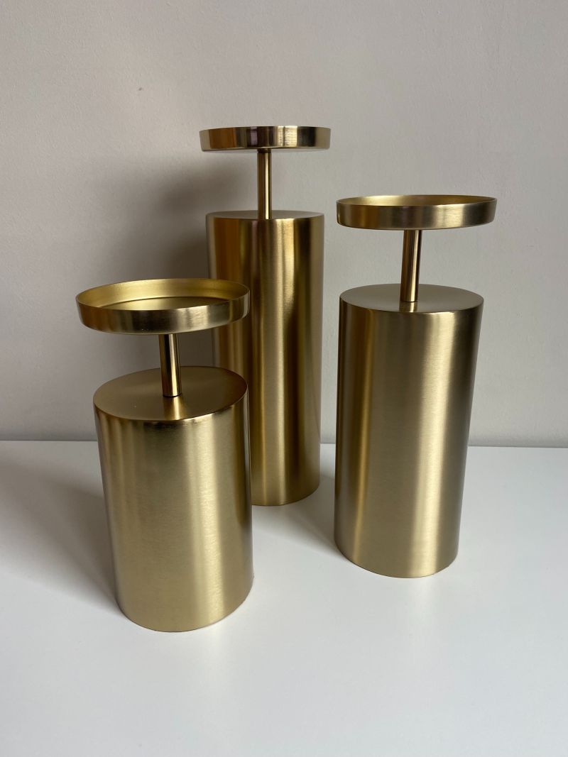 Three-piece brass pillar candlestick set presented as a decorative home accent for modern interiors