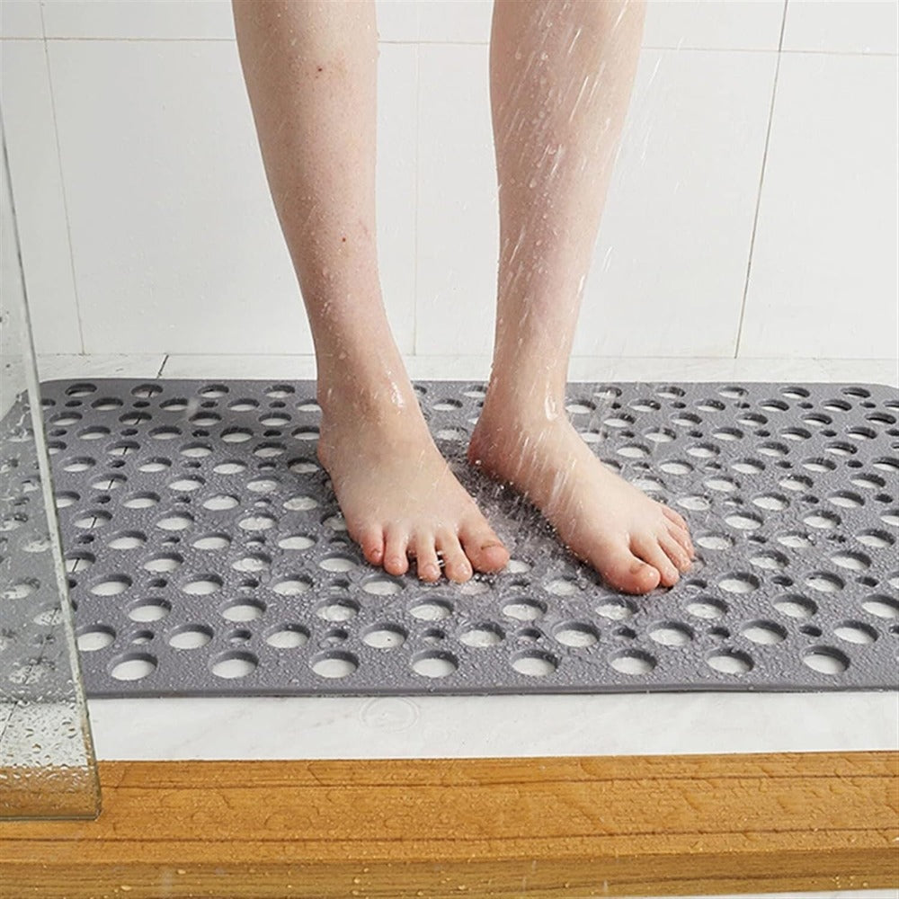 Non-slip rubber bath mat with perforated surface placed on wet bathroom tile