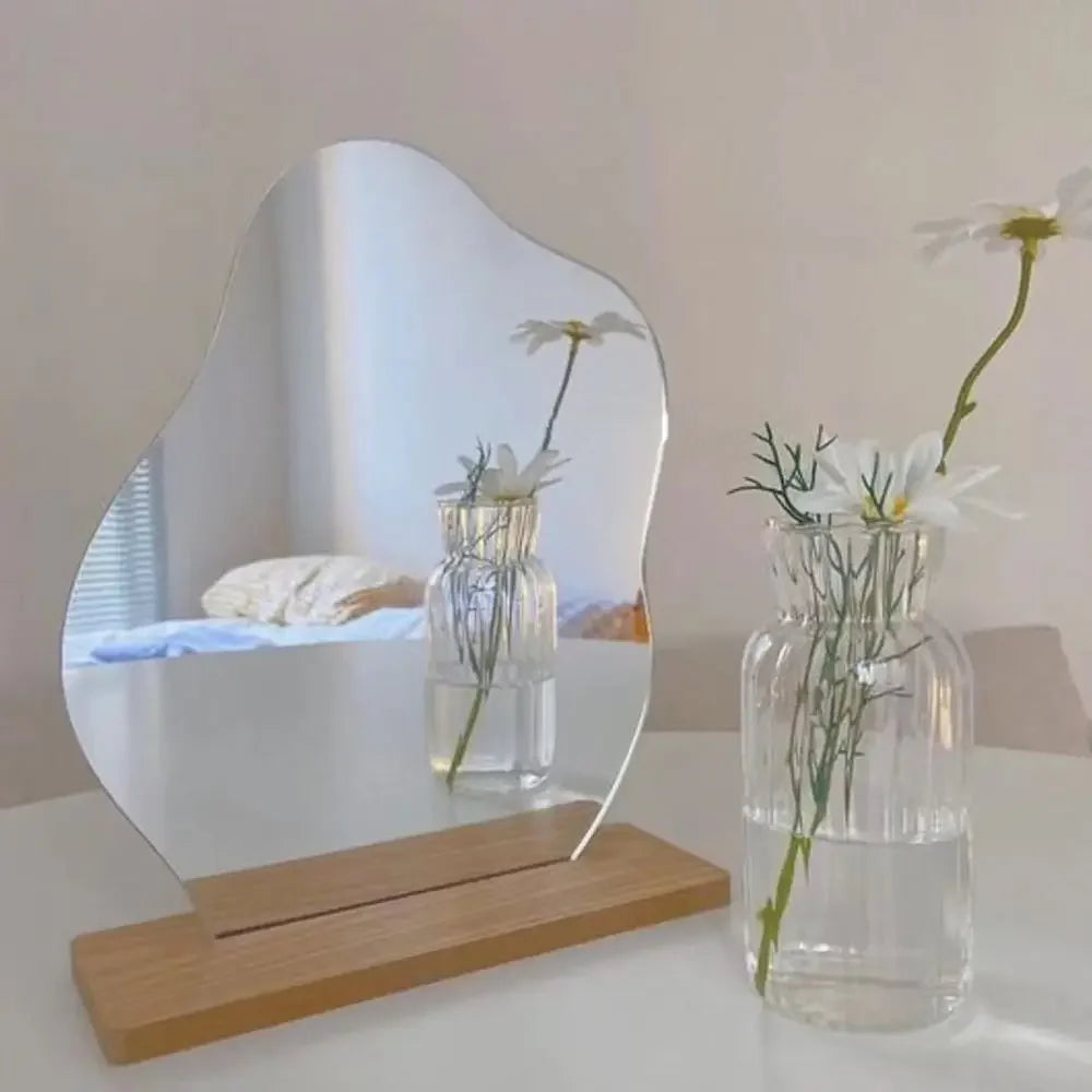 Organic-shaped frameless mirror with a sculptural wooden base for tabletop display