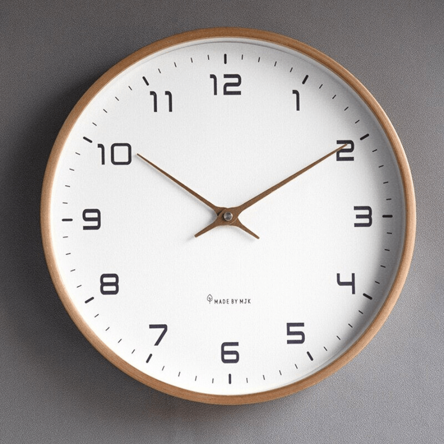 Minimalist wooden wall clock with clean dial face mounted on a light interior wall
