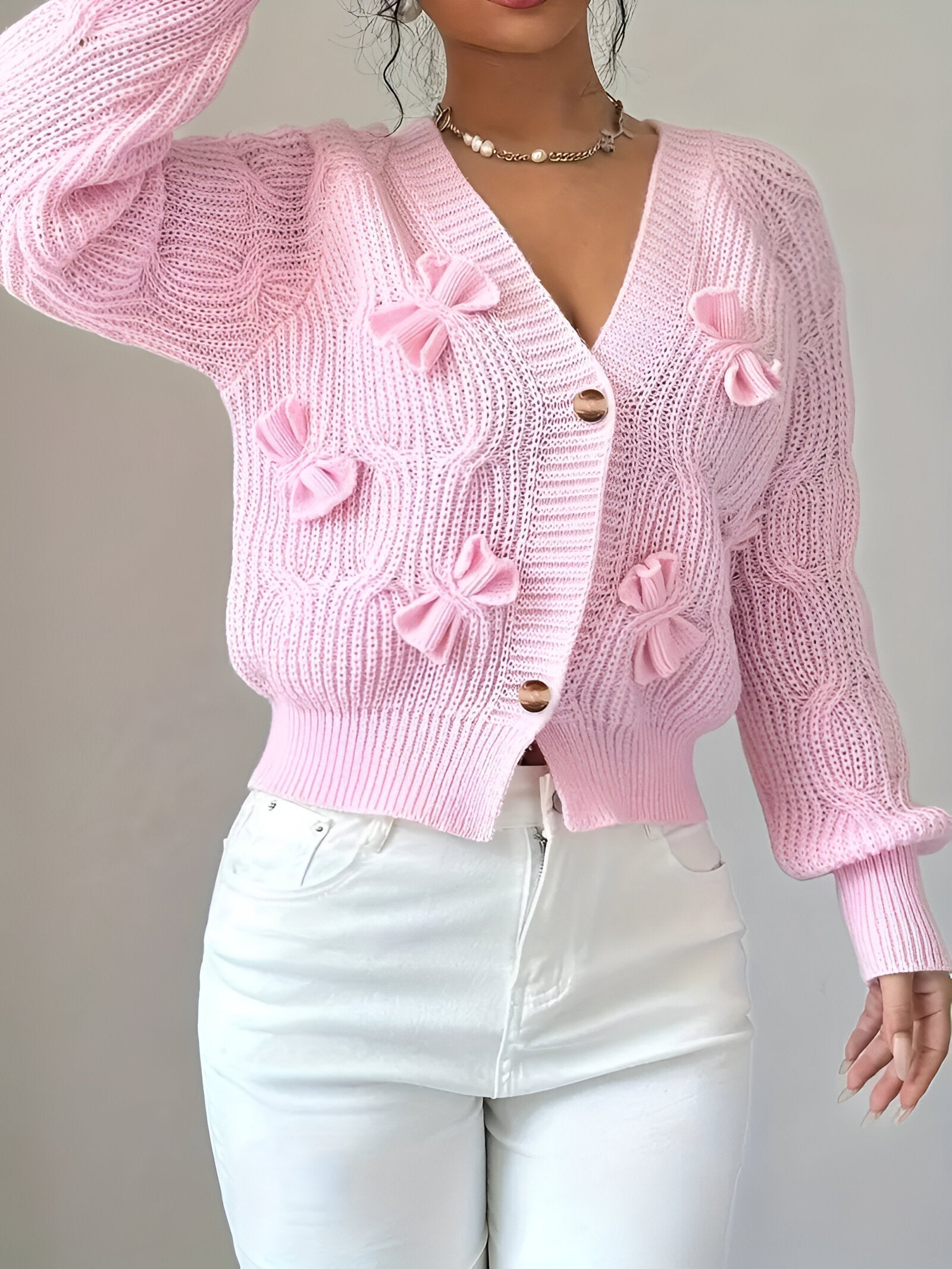 Women's knitted cardigan with textured pattern and decorative bows, three-quarter front view