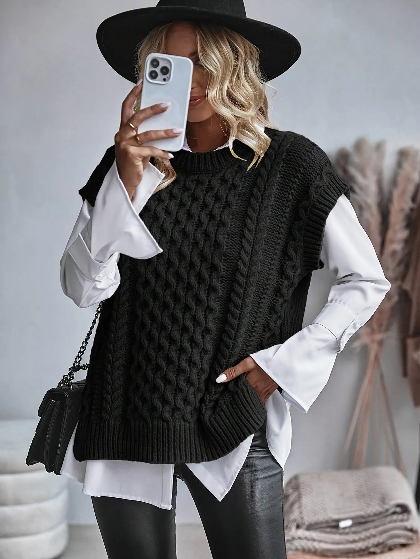 Women's cable knit vest layered over a long-sleeve top, styled for autumn and winter